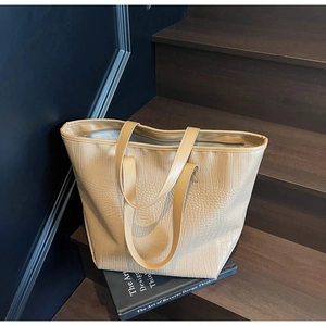 Minimalist khaki stone-patterned tote bag on a wooden step with elegant shadows