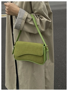 Street style view of a sage green suede patchwork underarm bag worn with a beige trench coat