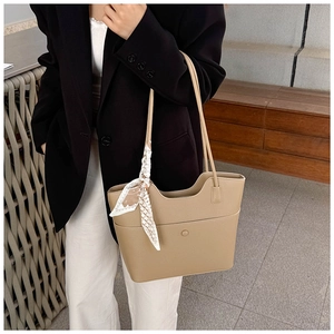 Detail of khaki tote bag with litchi texture leather and elegant floral scarf decoration