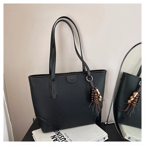 Detail of black lychee grain tote bag with beaded tassel and fashion embossed logo