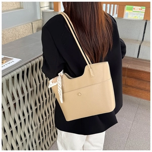 Detail of beige lychee pattern tote bag with decorative silk scarf on the shoulder strap