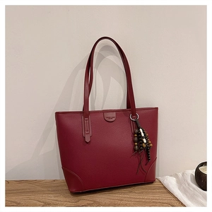 Macro detail of wine red pebbled leather tote bag with stylish beaded tassel accessory