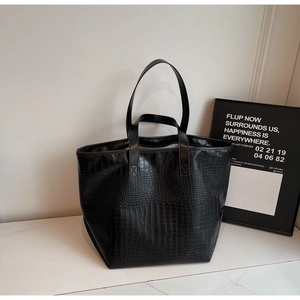 Detail of black crocodile embossed tote bag featuring dual handles for shoulder and hand carry