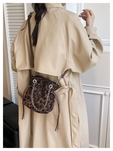 Lifestyle view of leopard print bucket bag with chain strap styled on a trench coat