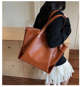 Close-up of brown crocodile embossed tote bag texture with long shoulder strap