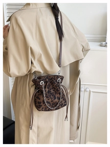 Close-up of leopard print drawstring bucket bag with silver chain and brown leather strap