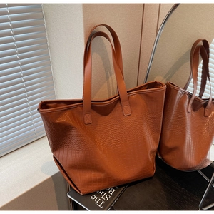 Close-up of brown faux leather tote bag with embossed crocodile texture in a warm home setting