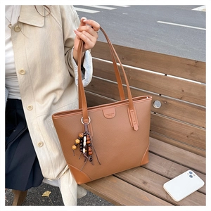 Close-up of brown pebbled leather handbag with colorful wooden bead charm detail