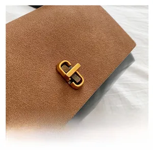 Macro detail of retro flap bag featuring brown suede texture and golden twist lock