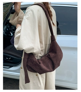 Detail of soft dark brown suede underarm bag with zipper closure and wide shoulder strap