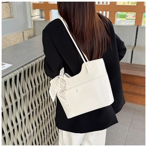 White pebbled leather tote bag with a checkered silk scarf detail on a model in a blazer