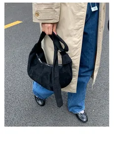 Street style view of a black suede crescent bag with knot detail and silver zipper