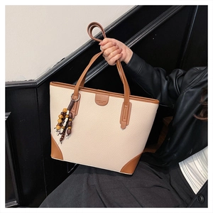 Detail of beige and brown contrast leather tote bag with decorative wooden beads charm
