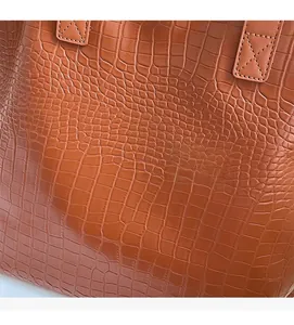 Detail of brown crocodile pattern faux leather with durable cross-stitch handle reinforcement