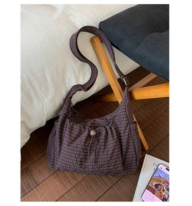 Détail du sac hobo à carreaux marron foncé avec cordon sur parquet en bois