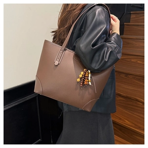 Detail of deep brown pebble leather tote bag with vintage style beaded charm accessory