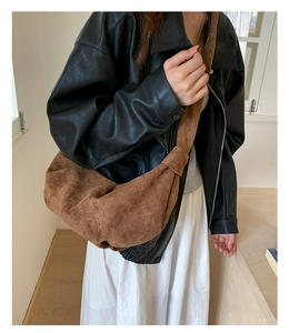 Deep brown suede crescent bag with knotted strap detail worn by model for casual style