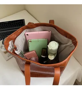 Top view of spacious brown crocodile-embossed tote bag with daily essentials inside