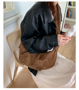 Brown suede hobo bag with pleated texture shown in a casual lifestyle indoor setting