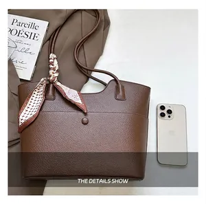 Detail view of the brown textured leather tote bag compared to a smartphone for size.