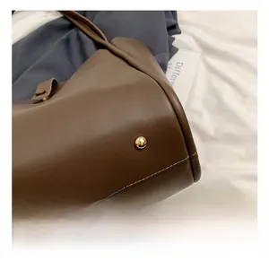 Détails des clous de protection dorés sur la base du sac cabas en cuir marron foncé