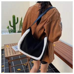 Détail d'un sac bandoulière en tissu noir avec bordure en fausse fourrure blanche