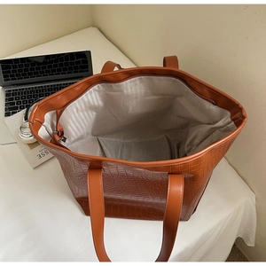Top-down view of spacious caramel brown tote with crocodile pattern and office essentials