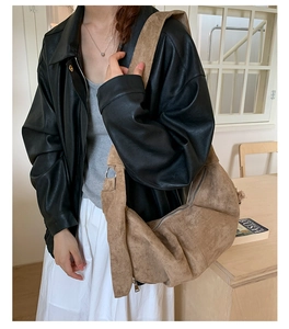 Close-up of a brown suede hobo bag with soft pleats and metal ring details on a model