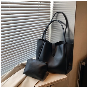 Détail d'un ensemble de sacs cabas noir en similicuir avec pochette sur un rebord