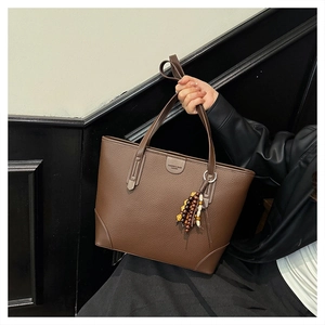 Brown litchi grain tote bag detail featuring colorful wooden bead tassel and leather logo