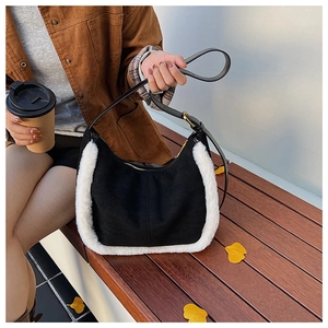 Gros plan sur un sac bandoulière en daim noir avec bordure en fausse fourrure blanche