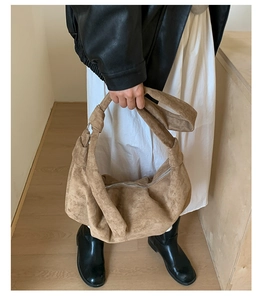 Close-up of brown suede shoulder bag featuring a unique knotted strap and silver zipper detail