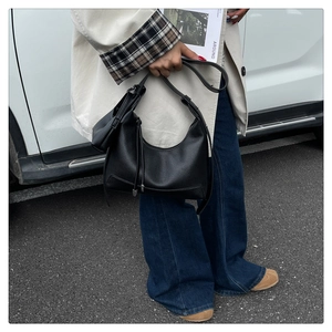 Detail einer schwarzen Hobo-Tasche aus strukturiertem Leder mit Reißverschluss am Model