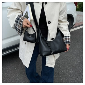 Detail von schwarzer Hobo-Bag aus Leder und kleiner Tasche am Model im Street-Style