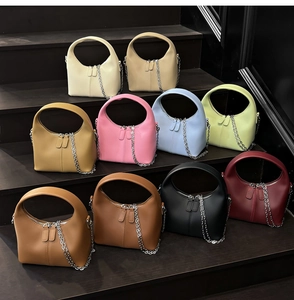 Multiple colorful crescent-shaped handbags featuring leather texture and silver chain straps