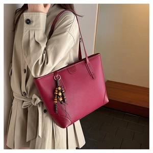 Detail of burgundy lychee leather tote bag with unique wooden bead tassel accessory