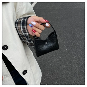 Detailaufnahme von schwarzem Lychee-Leder und Silberschnalle an einer kleinen Tasche