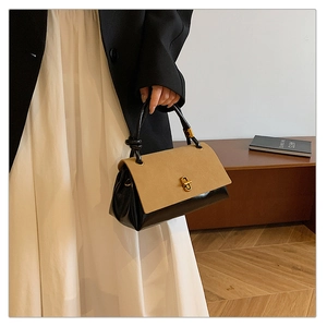 Close-up of contrast khaki leather flap and black body with golden turn-lock clasp