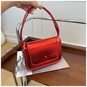 Detail of metallic red crossbody bag with white stitching and silver star pendant