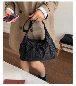 Détail du sac bandoulière en toile à carreaux avec cordon de serrage et boucle