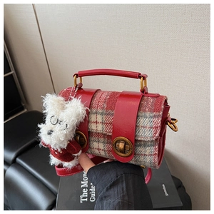 Détail d'un sac à carreaux rouge avec boucles vintage et pendentif ours en peluche
