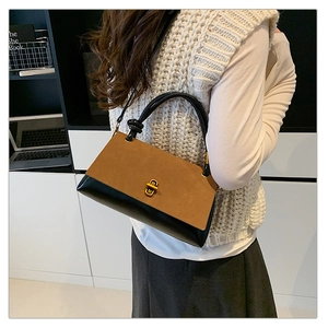 Detail of retro flap bag with brown-black splicing and a golden twist-lock closure