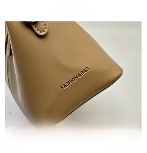 Detail of tan leather bag with embossed 'FASHION & BAG' text and contrast cream stitching