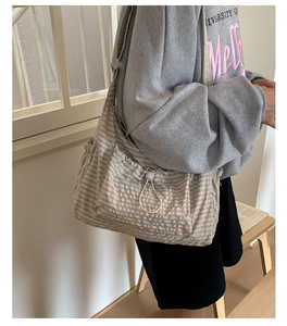 Détail du sac bandoulière en toile rayée avec poches à cordon et large bandoulière