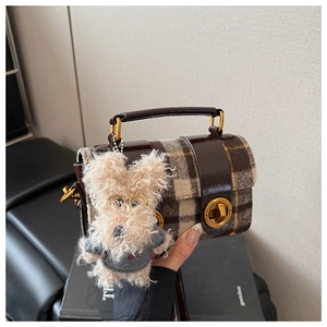 Gros plan du petit sac à carreaux avec poignée en cuir et pendentif chiot mignon