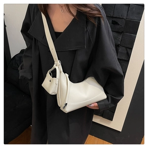 Detail der cremefarbenen Leder-Baguette-Tasche mit Mini-Etui auf schwarzem Mantel