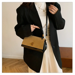 Detail of contrast handbag with khaki flap, black body, and golden twist-lock closure