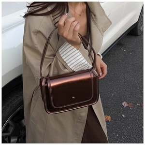 Detail of metallic bronze crossbody bag with round buckle and contrast stitching