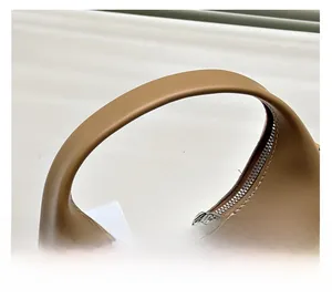 Detail view of smooth brown leather tote with arc handle and silver dual zippers