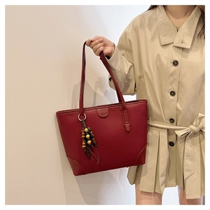 Detail of burgundy textured tote bag with lychee grain finish and wooden bead tassel